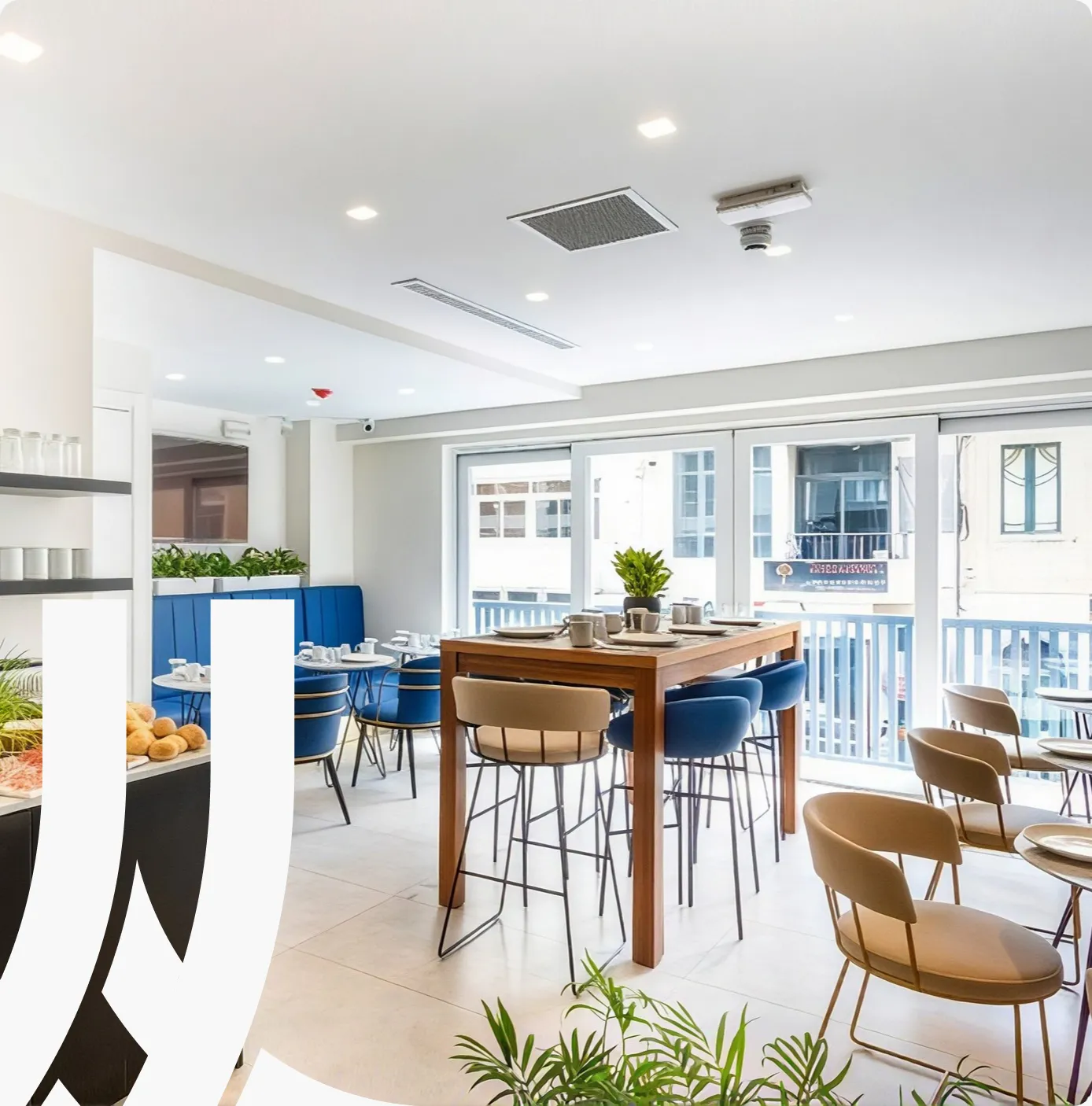 G Hotel’s bright breakfast room with a wooden table, bar stools and blue chairs
